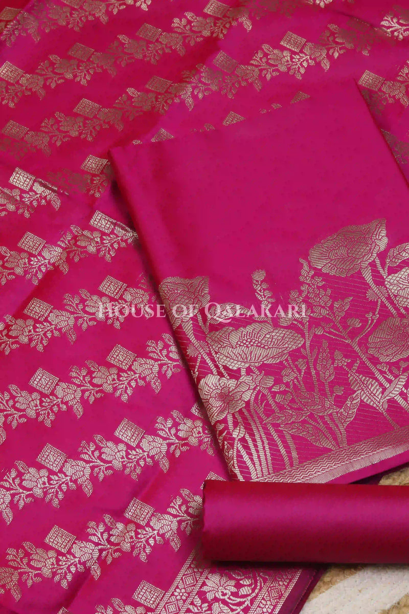 Banarasi silk Unstitched Dress Material in Rani Pink and with lotus floral border and diagonal striped zari work dupatta – product